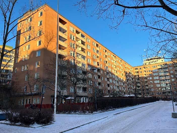 Flerbostadshus i Stockholm med tegel­fasad och balkonger under vintertid, fotograferat i samband med fönsterrenovering i en bostadsrättsförening.